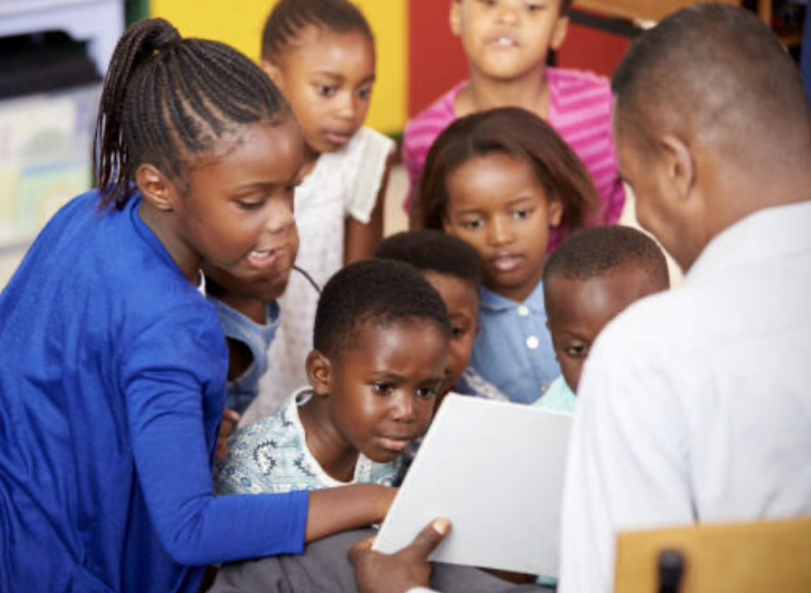 Upper Primary pupils gathered around their teacher reading together